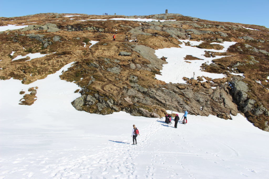 Group of people skiing on a downhill snowy slope while hiking in Bergen, Norway - from Mt. Ulriken to Mt. Fløyen.