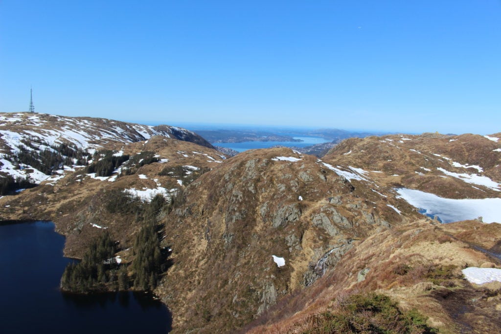 Rugged mountains dusted with snow on top. While hiking in Bergen, Norway, you will encounter other hikers from time to time.