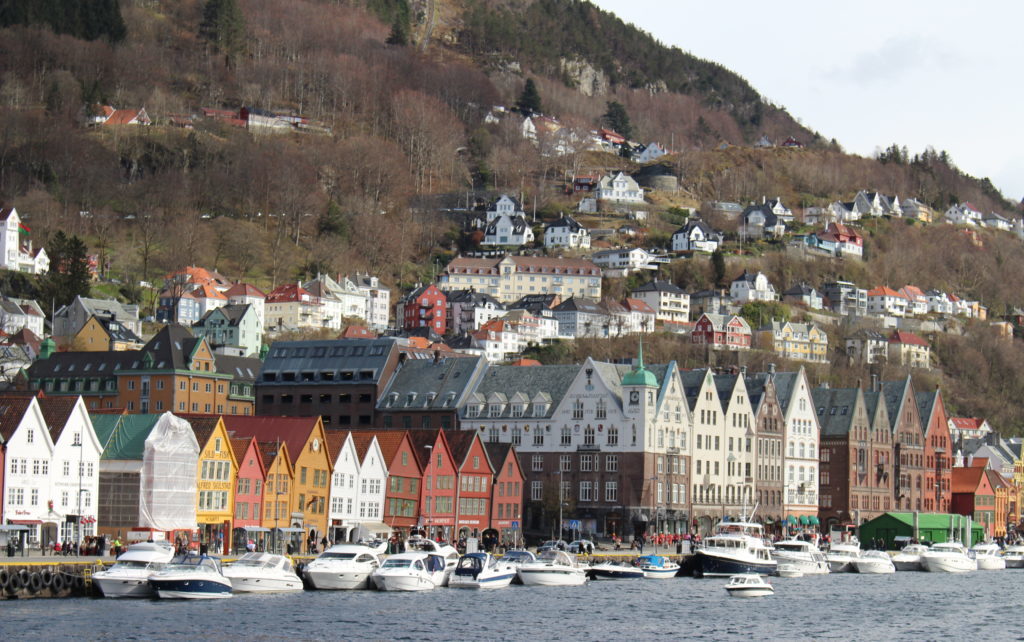 Tall, colorful buildings and boats at the foot of a mountain