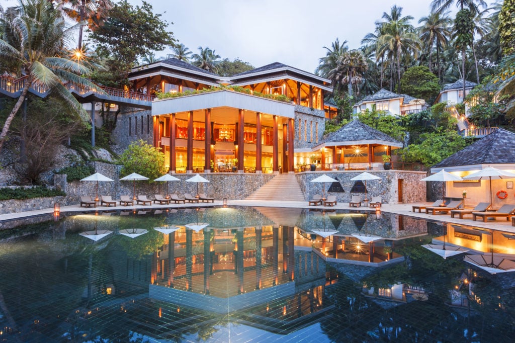 Luxurious pool surrounded by lounge chairs and umbrellas at The Surin Phuket