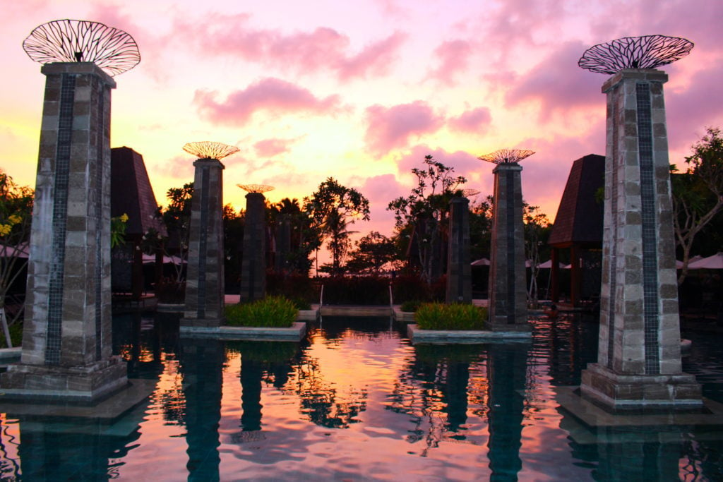 The pool at the Sofitel Bali Nusa Dua Beach Resort against orange-pink skies