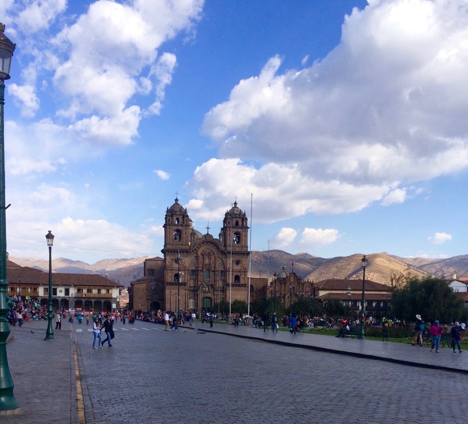A cathedral in Cusco with crowds of people roaming around during daytime.  Spend a few days in Cusco before you go on your Inca Jungle Trek adventure.