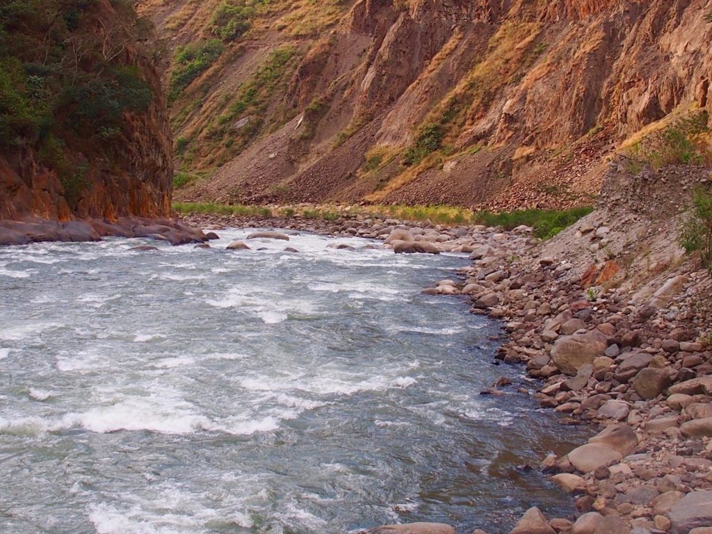 River waters rushing at the foot of the mountains surrounded by pebbles and larger rocks. This guide will give you tips for your Inca Jungle Trek adventure.
