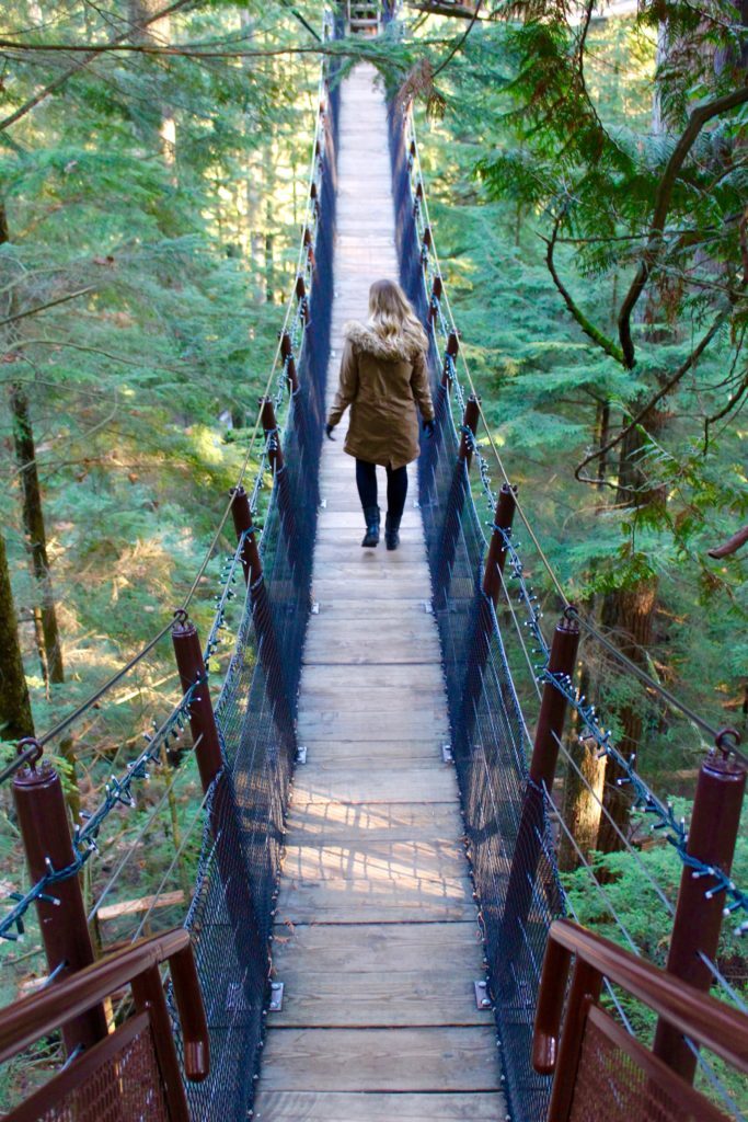 Maddy walking on the Capilano Suspension Bridge. Wondering what to do in Vancouver? Connect with nature by visiting this park.