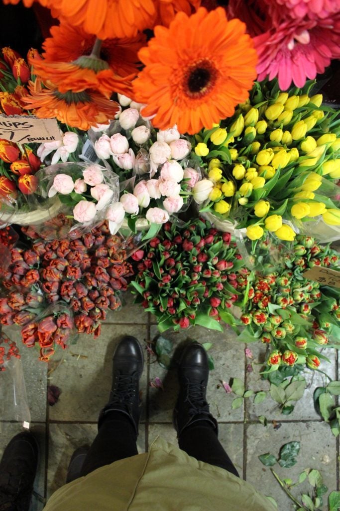 Standing in front of beautiful colorful bouquets of flowers. Wondering what to do in Vancouver? The Granville Island Public Market offers many things to do and see.