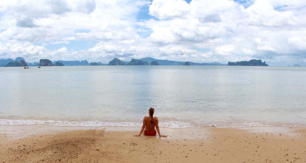 Maddy sitting on the sandy beach enjoying the gorgeous views while island hopping in Thailand