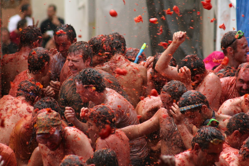 Crowd of people throwing tomatoes on one another in celebration of La Tomatina