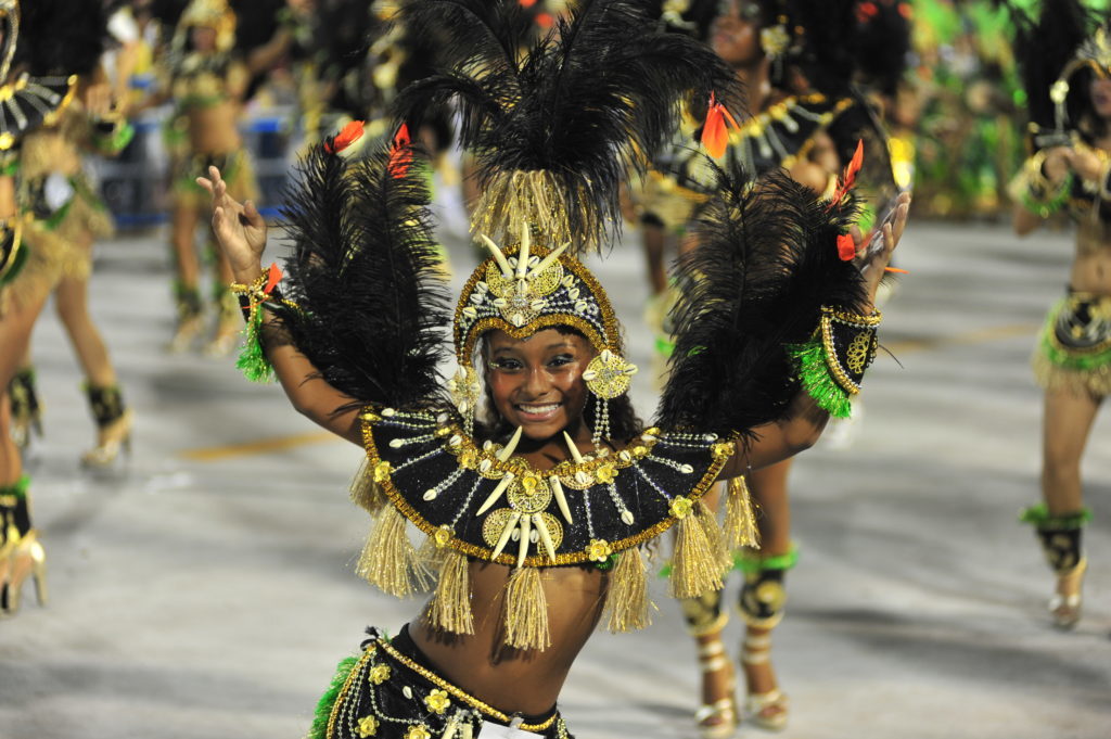 Beautiful girl in costume dancing for the Rio Carnival. This party is one of the 20 festivals to experience in your 20s.