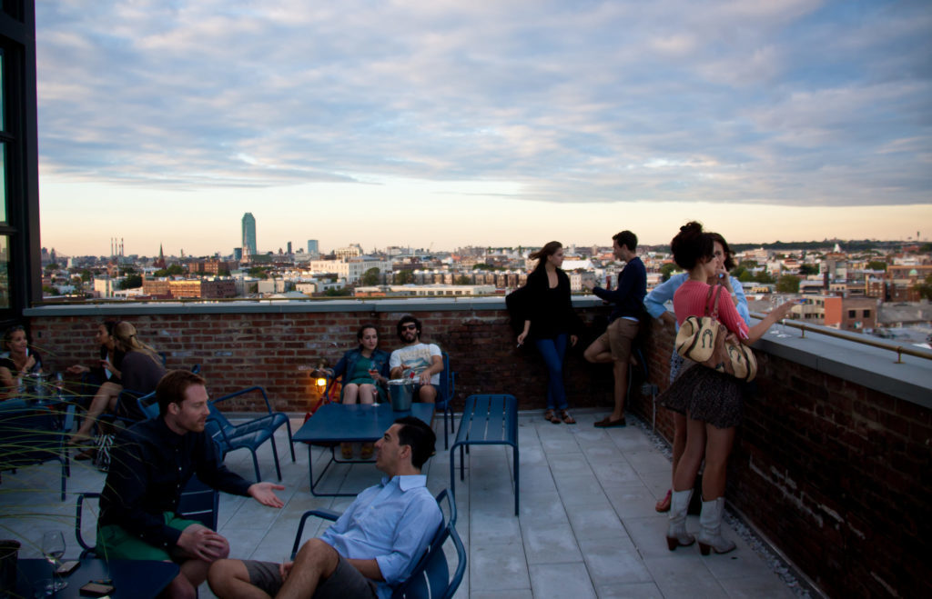 People drinking and talking at a rooftop bar in NYC