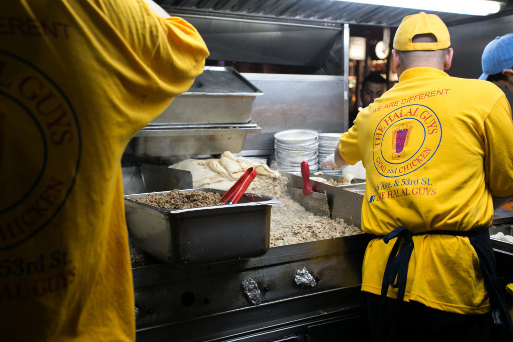 People cooking inside of the Halal Guys food cart in NYC