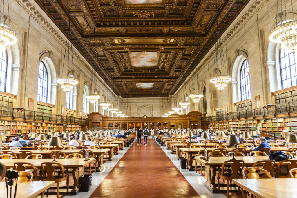 The beautiful interior of the New York Public Library with people sitting and reading