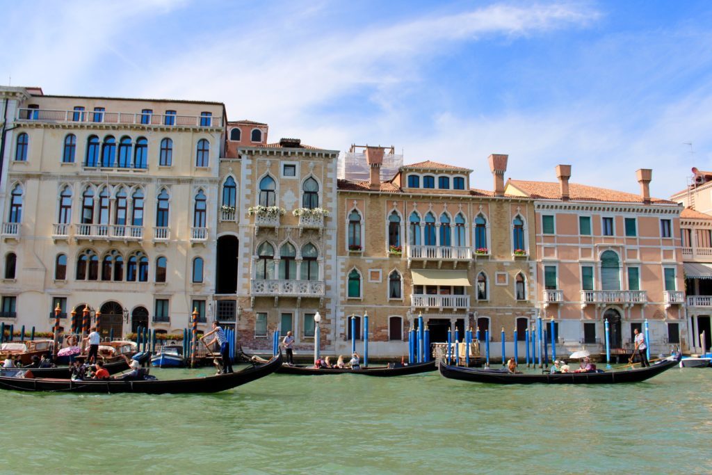 Multiple gondolas in Venice as they pass by the beautiful buildings