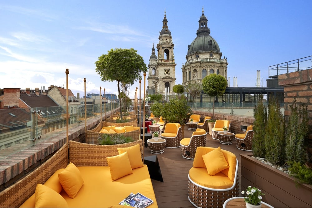 Cozy chairs and sofas in brown and mustard colors on the rooftop bar overlooking the beautiful views of Budapest