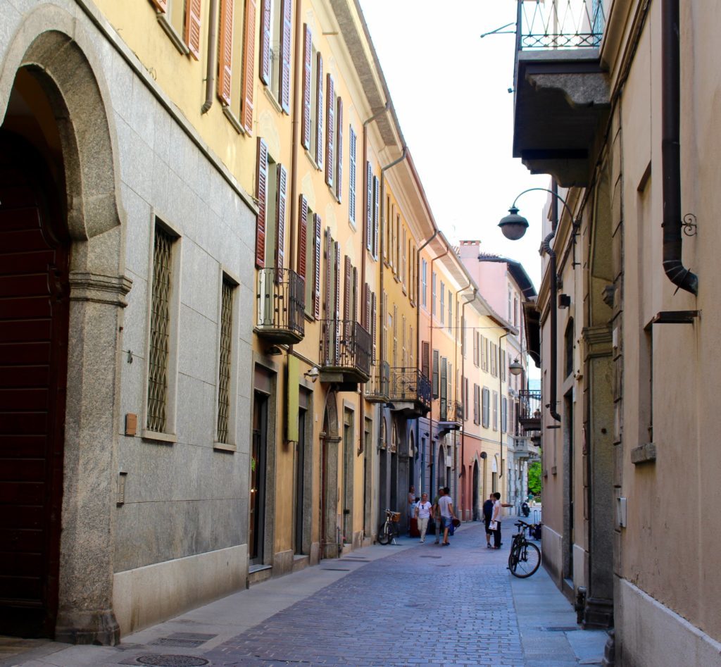 Narrow cobblestone street in Como. This Lake Como travel guide provides information on what to do in Como to make your visit worth it.