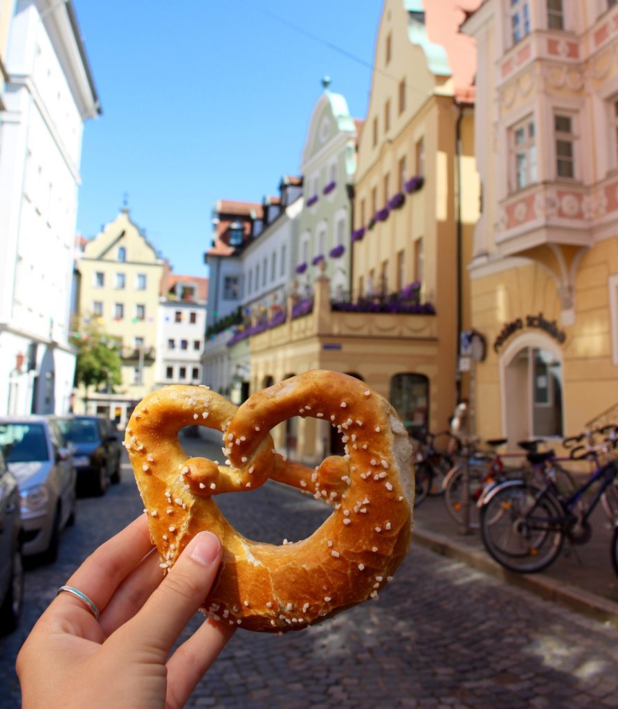 Holding up a pretzel while on a street in Regensburg, Germany