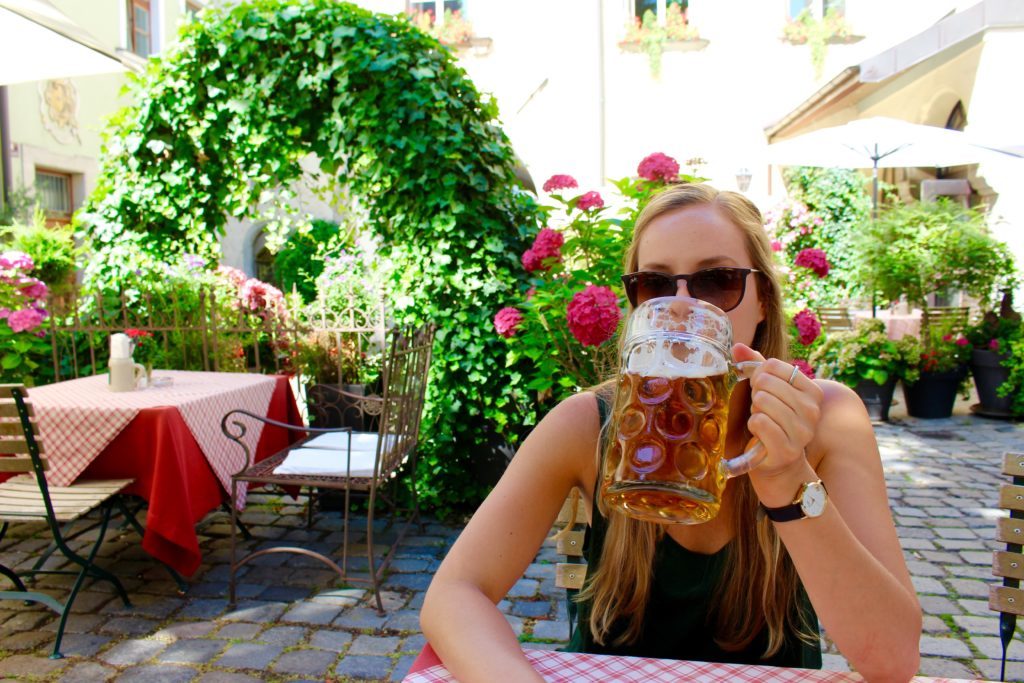 Maddy taking a sip of beer in a biergarten during daytime
