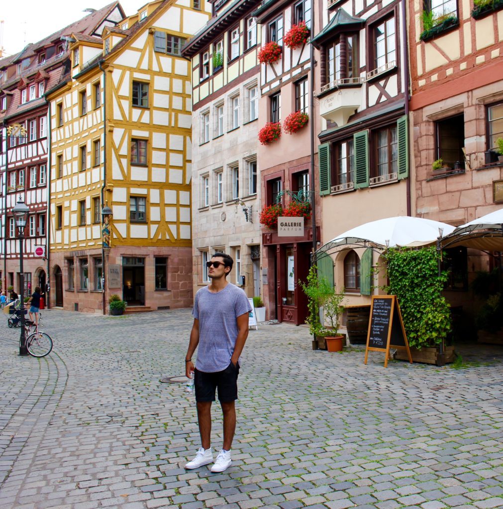 Mauricio, blogger, standing on a cobblestone street in Nuremberg. Roaming the beautiful cobblestone streets lined with cafes is one of the best things to do in Nuremberg.