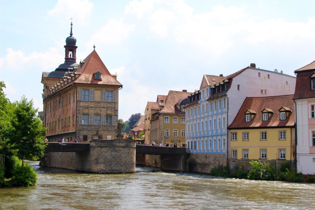 The Regnitz River passing below a bridge with people walking over it. The town of Bamberg is considered one of the fairy tale towns in Germany.
