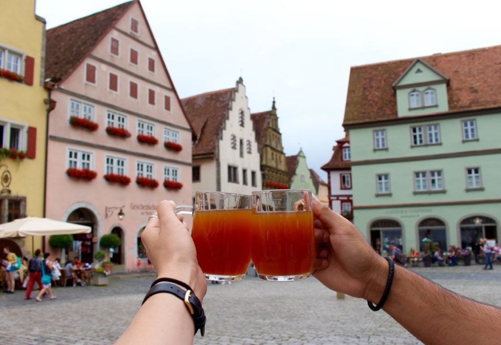 Holding up two mugs of drinks at Rothenburg ob der Tauber - one of the fairy tale towns in Germany