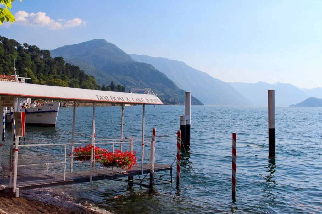 The shores of Bellagio with sun-streamed mountains in the background.