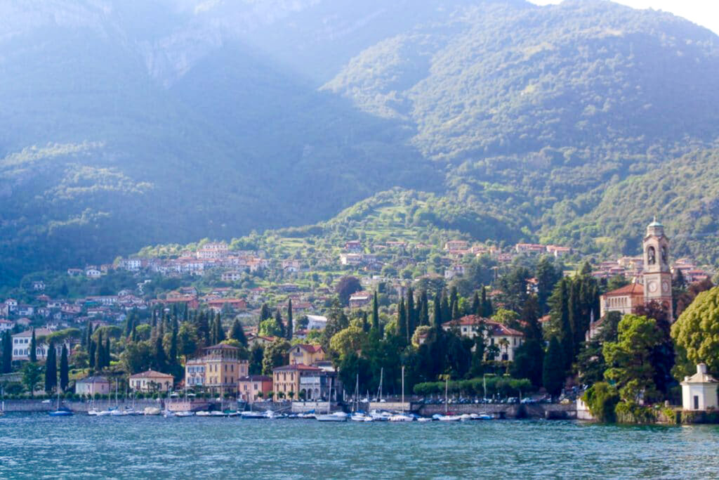 View of the town of Bellagio from the lake, with the sun streaming over the mountains in the background