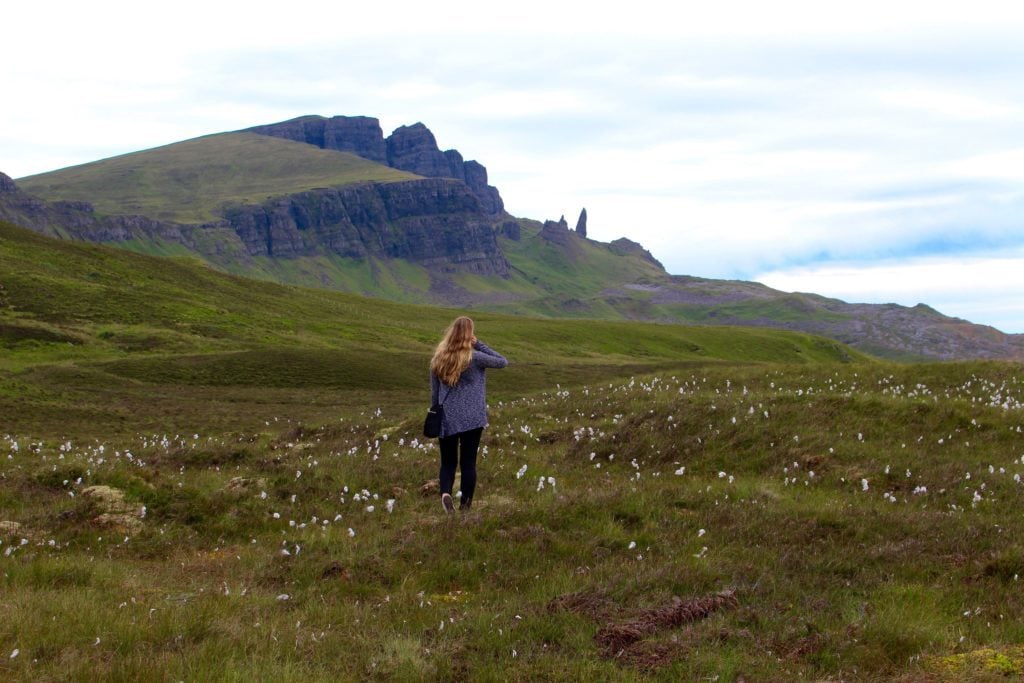 Maddy, blogger, standing on an open field with grass and flowers while traveling in Scotland in August