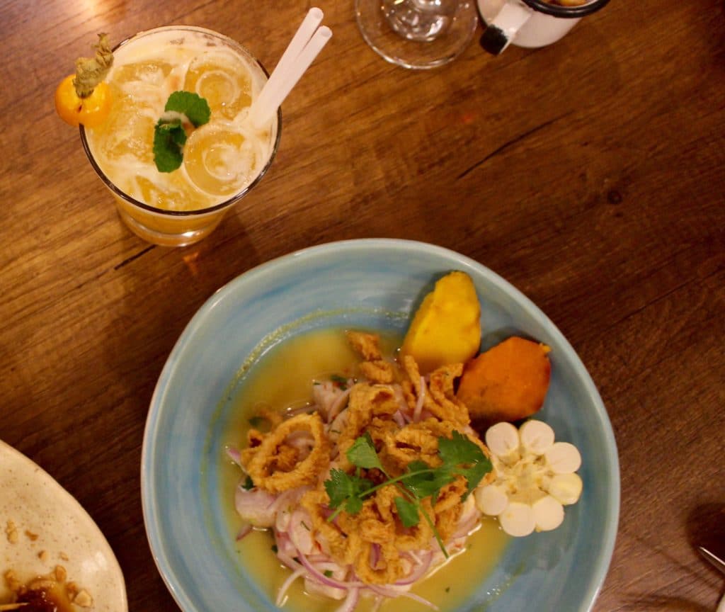 A bowl of delicious Peruvian ceviche beside a glass of iced drink. Make sure to try at least one plate of ceviche during your three days in Cusco.