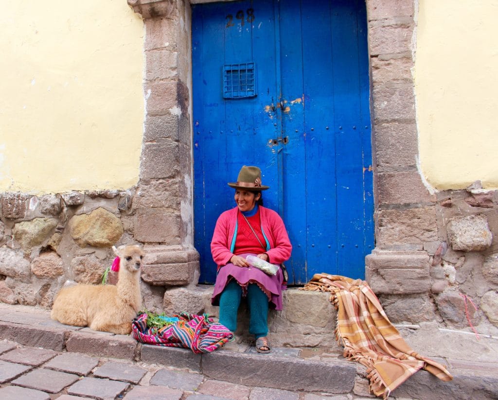 A local woman and an alpaca sitting on a doorstep