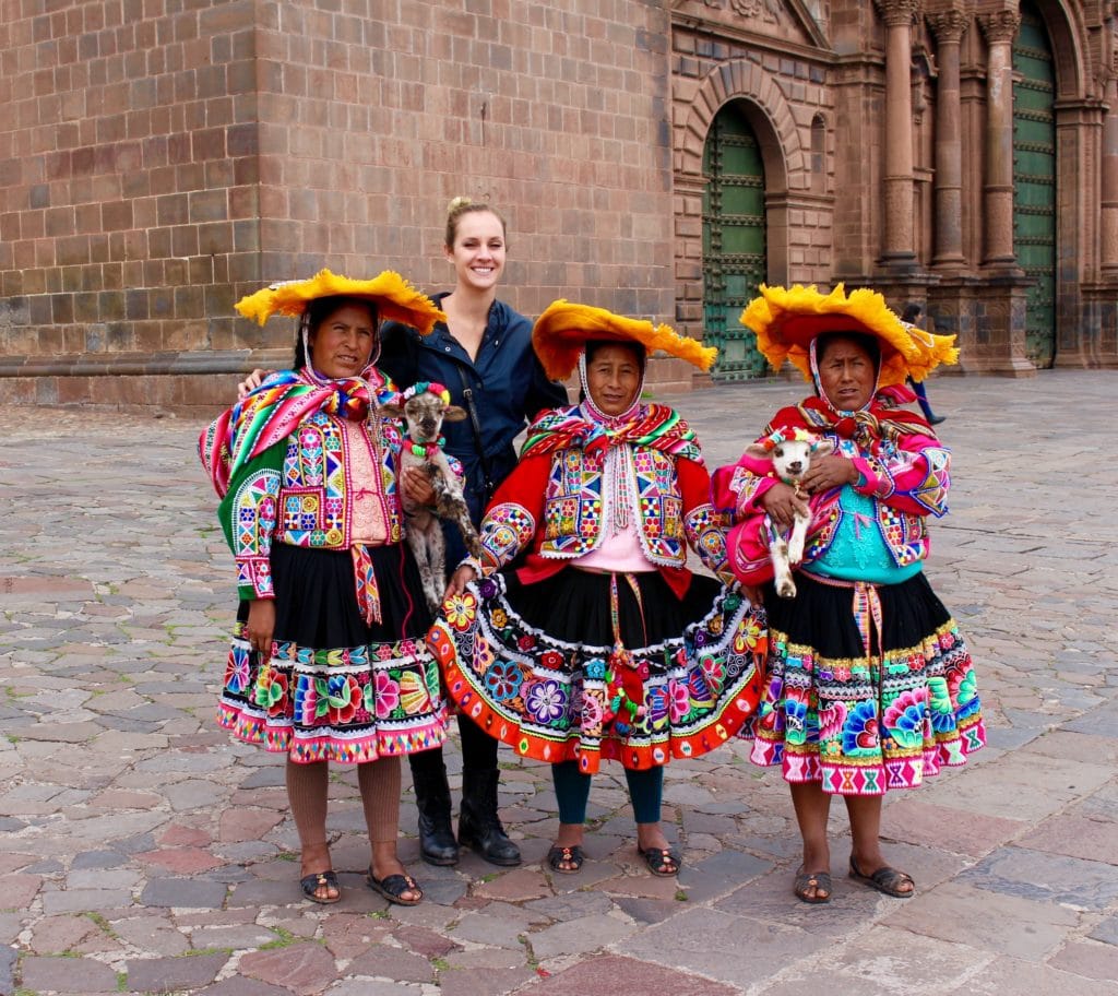 Maddy posing for a photo with three Cusco women dressed up in colorful, traditional clothing