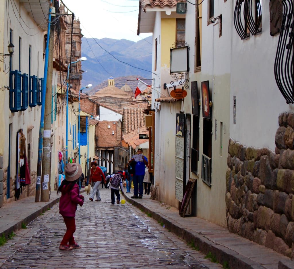 Cobblestone downhill street with people and kids walking