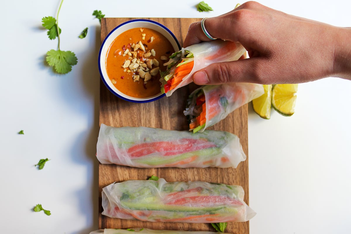 A fresh spring roll about to be dunked in peanut sauce. 