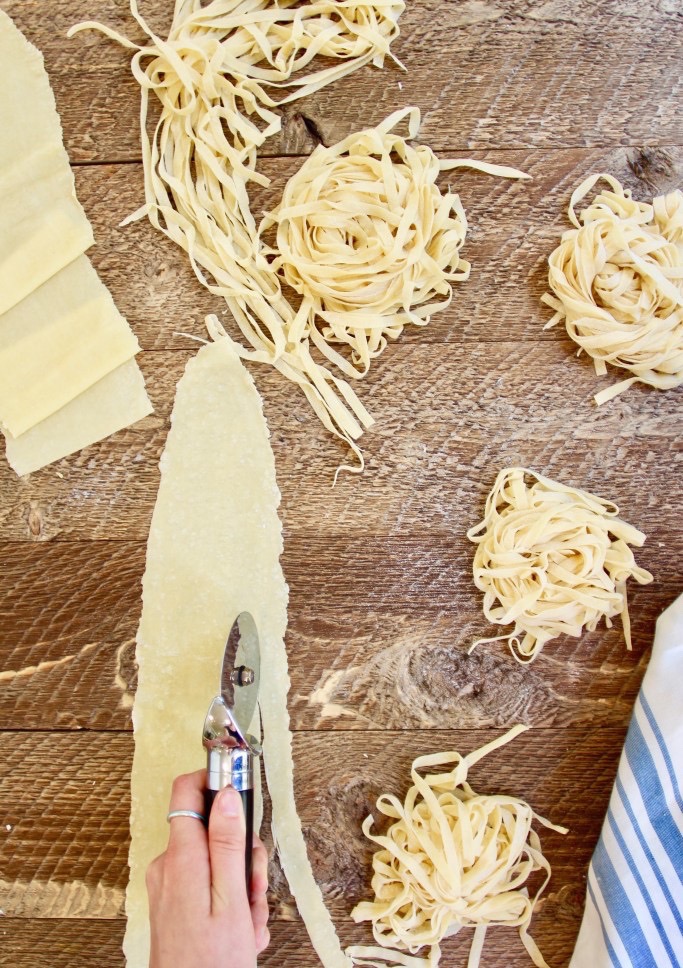 Slicing flattened dough into thin sheets to make a homemade pasta recipe