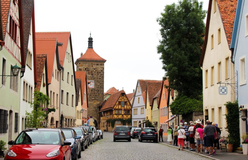 Cars parked by a street as people walk on the other side of the road