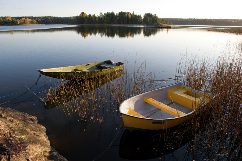 Two wooden boats docked on calm waters near an island