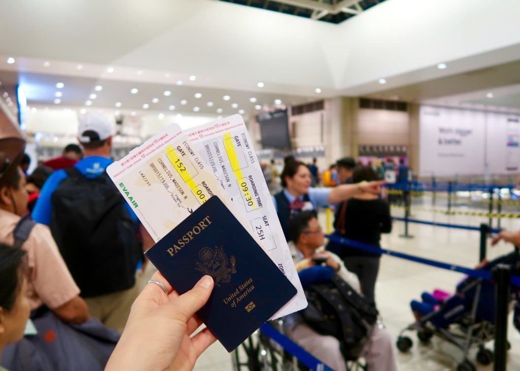 Holding up a passport and plane tickets in an airport