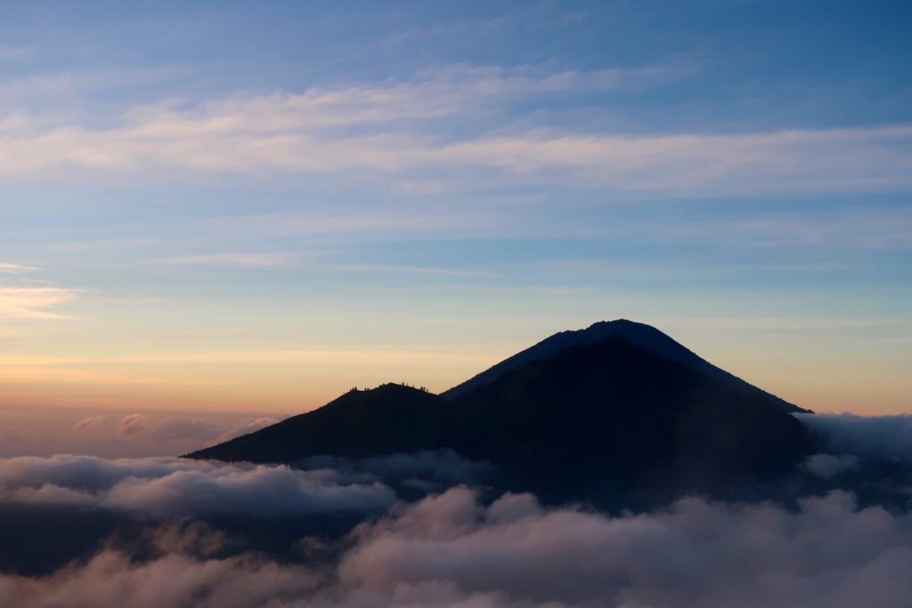 Mountain peak above the thick fogs during sunrise. Your trip will not be complete without hiking Bali's Mount Batur at sunrise.