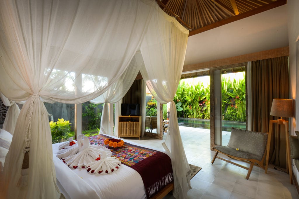 Relaxing bedroom with floor-to-ceiling windows, white curtains, and towels formed as swans on the bed