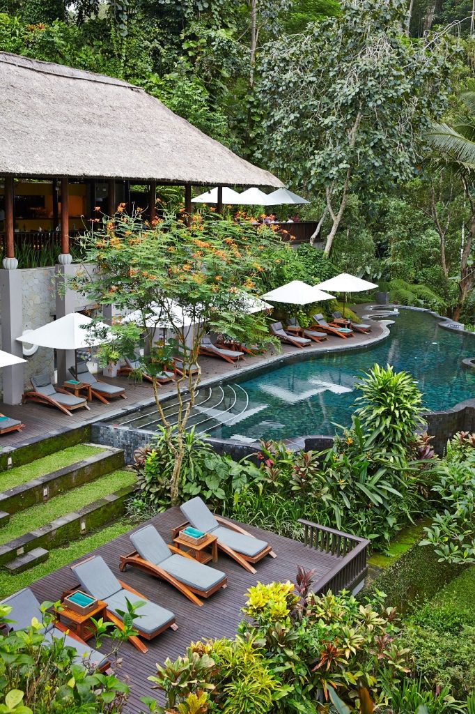 River cafe pool lined with outdoor lounge chairs and umbrellas at Maya Ubud Resort & Spa - one of the best places to stay in Ubud