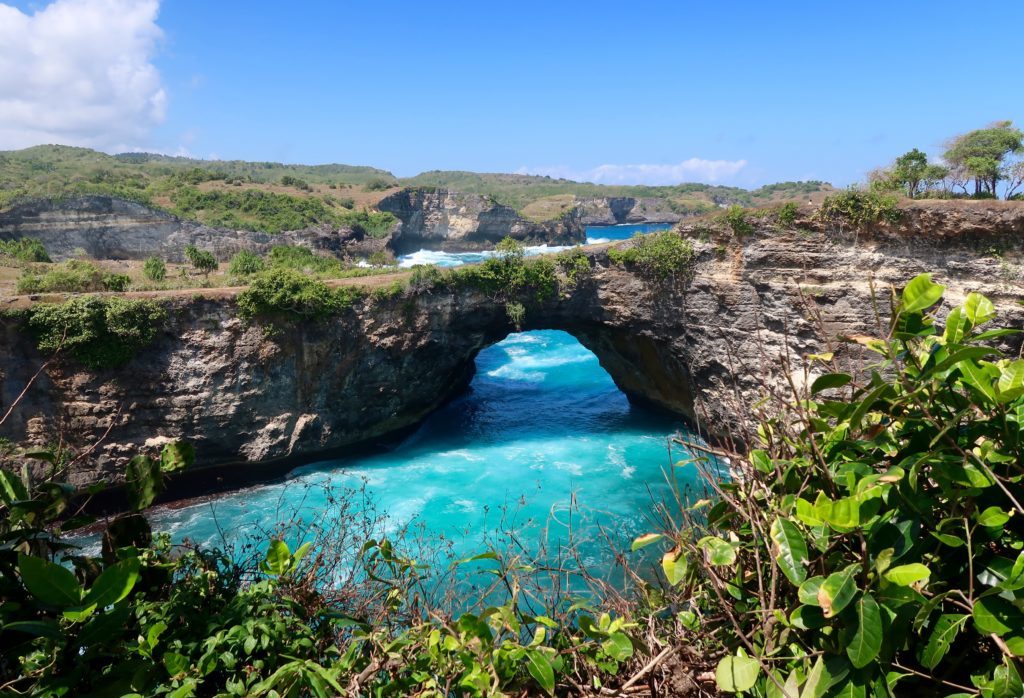 Blue river waters under a stone bridge surrounded by lush trees in Nusa Penida. If you're looking for the best things to do during your three weeks in Bali, this is the perfect guide to consider.