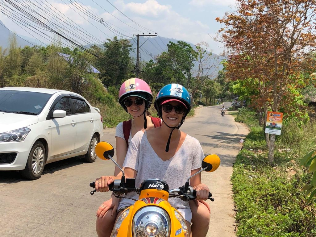 Maddy and a friend riding a yellow motorcycle on the road