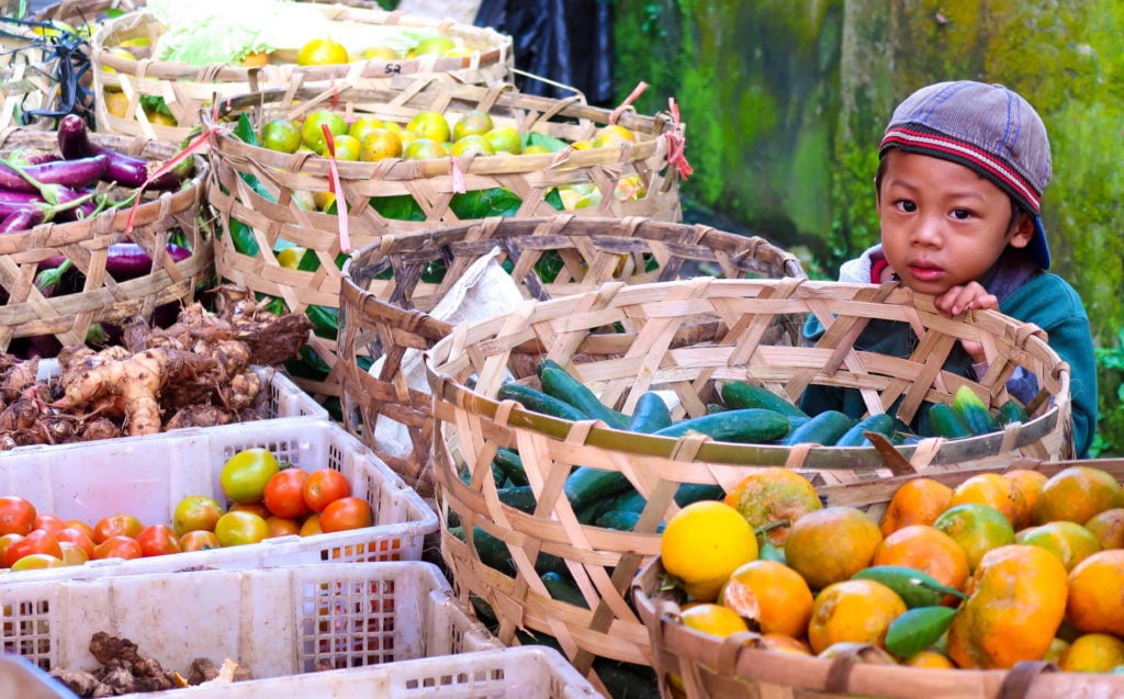 A Balinese child holding one of the baskets with fresh fruits and vegetables. Don't forget to buy fresh produce from local markets during your three weeks in Bali.