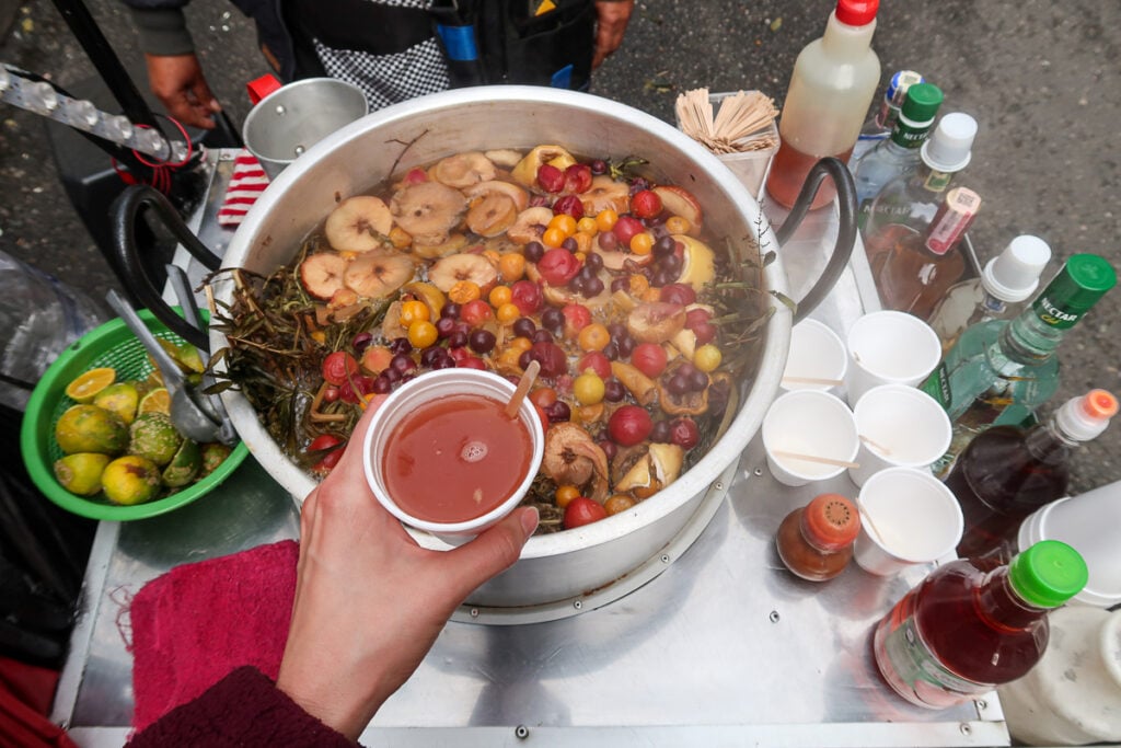 Large pot of stewing fruit and a cup of hot broth in Bogota, Colombia