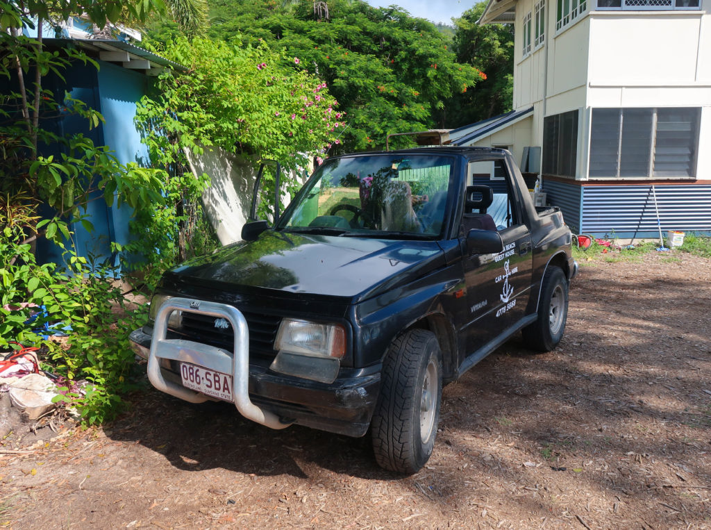 Black rental car parked near a house. Renting a car will let you explore Magnetic Island on your own pace.