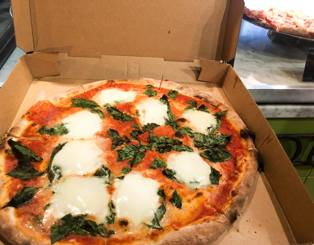 Tasty takeaway pizza garnished with basil. Wondering where to eat in Byron Bay? Get your box of pizza from Slice.