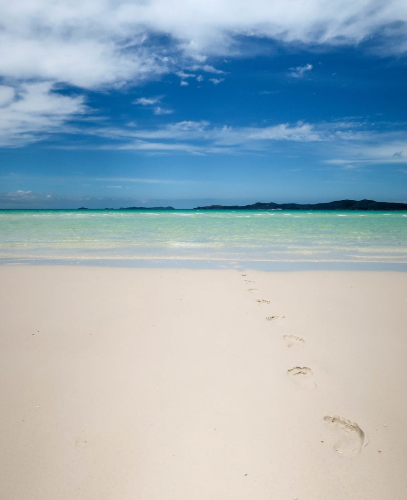 Footsteps heading towards the waters on the white sand beach