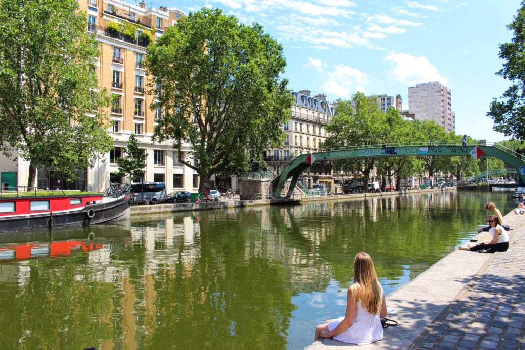 Maddy hanging out at the Canal Saint-Martin. Discovering Canal Saint-Martin is one of the best things to do in Paris.