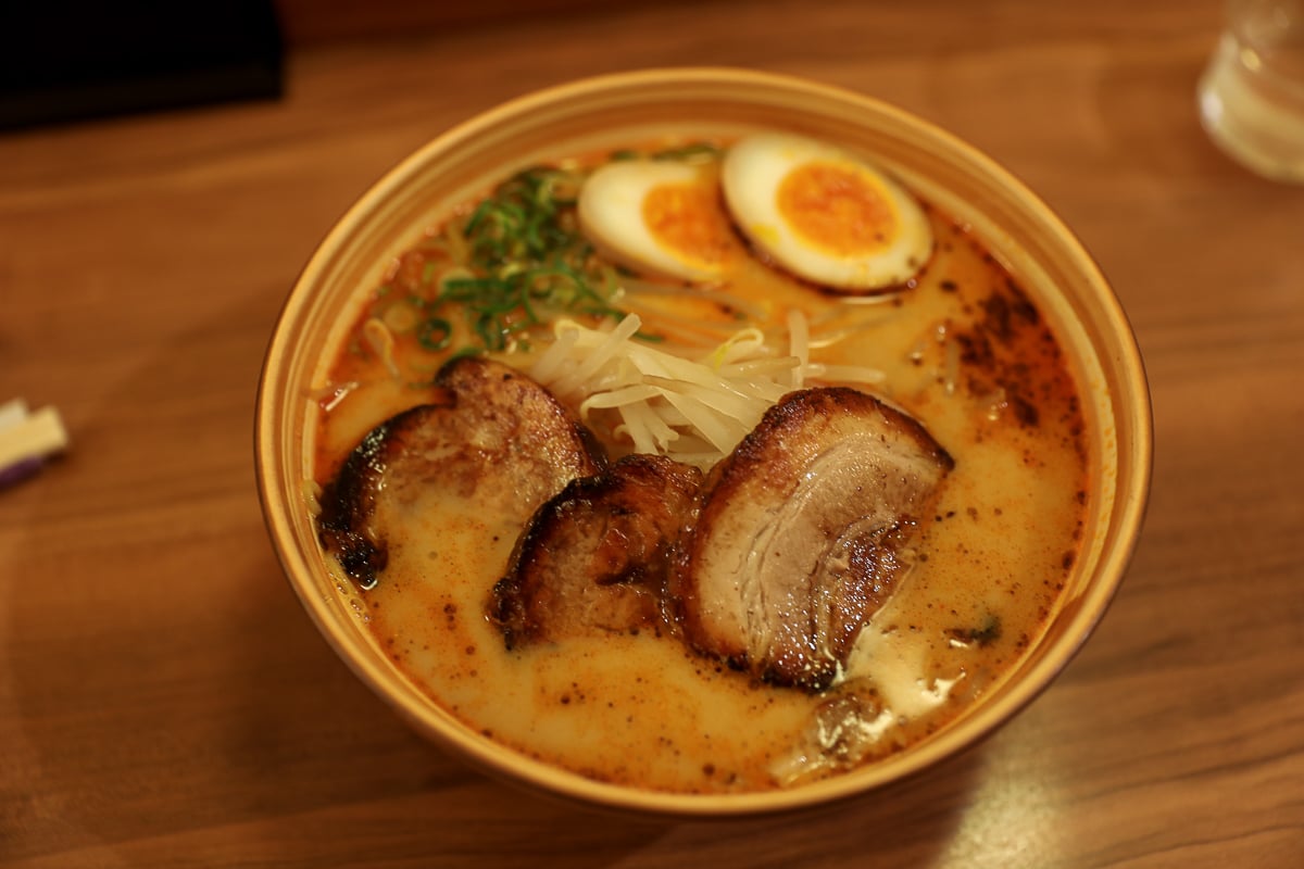 Bowl of Japanese ramen in Kyoto topped with chashu pork, soft-boiled egg, bean sprouts, and green onions in Kyoto