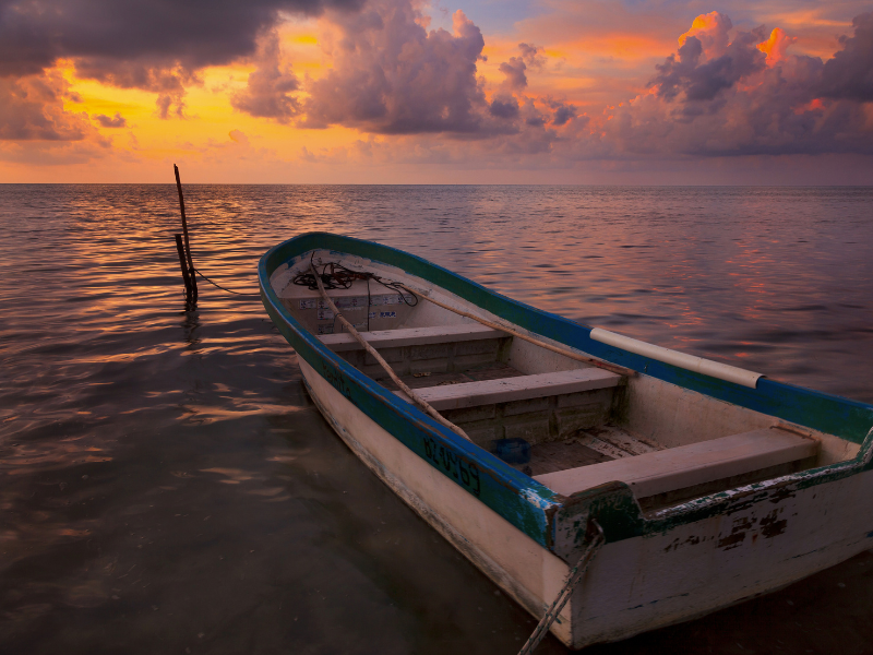 The sun rising over the Caribbean with a boat floating in the water