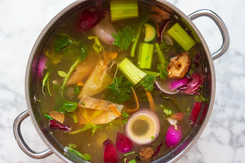 To make homemade veggie stock with your kitchen scraps, all you need is a big pot, some frozen veggie scraps, and water. You can also add extra ingredients to boost the flavor.