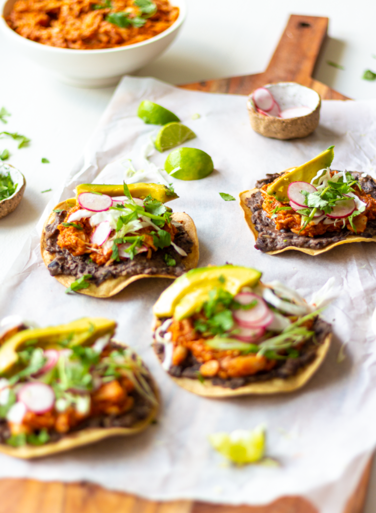 Jackfruit Tostadas make for an easy and delicious Mexican-inspired dinner! These tostadas are crispy, slathered with flavor-packed refried black beans, then topped with smoky, meaty pulled jackfruit. Quick, healthy, and flavor-packed, you'll love this Vegan Jackfruit Tinga in tostadas, tacos, and burritos!